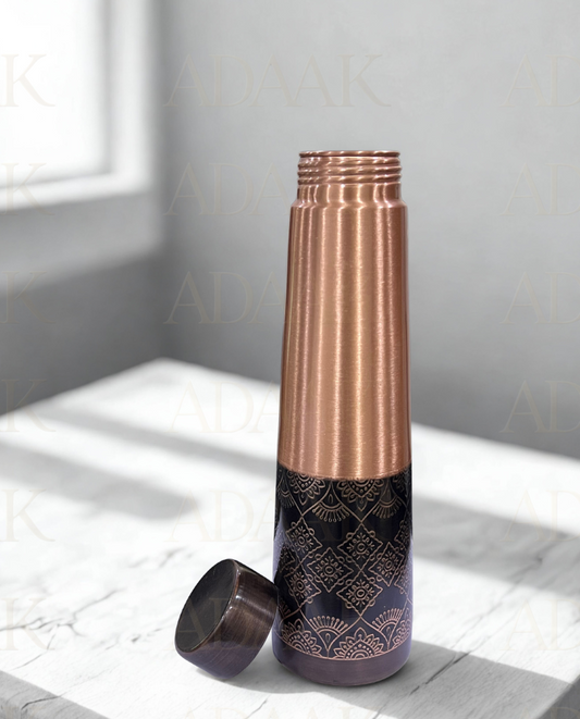 Copper and black patterned water bottle on a light surface with a neutral background