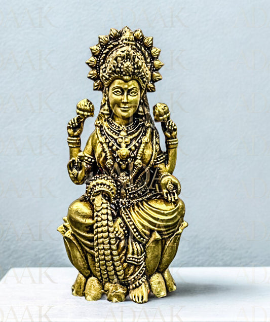 Brass statue of a deity on a white platform with a light gray background