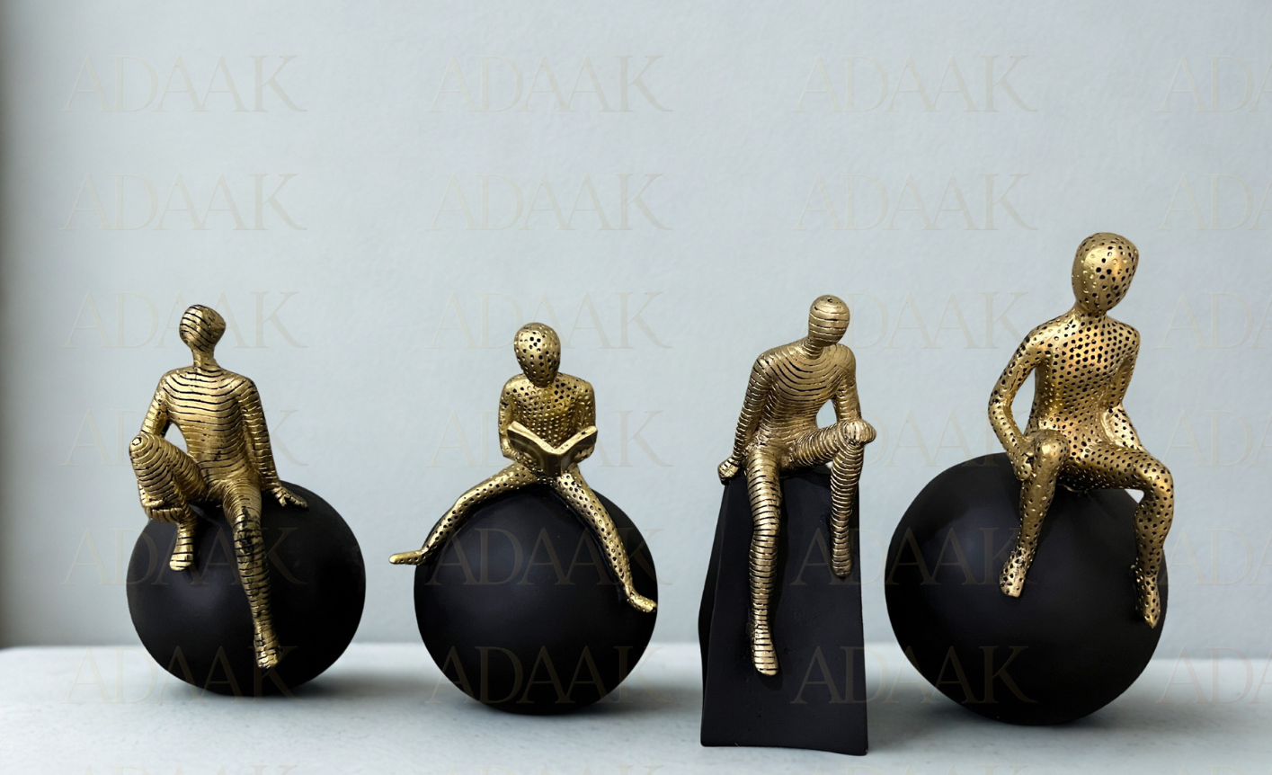 Four gold figurines on black spheres against a light gray background