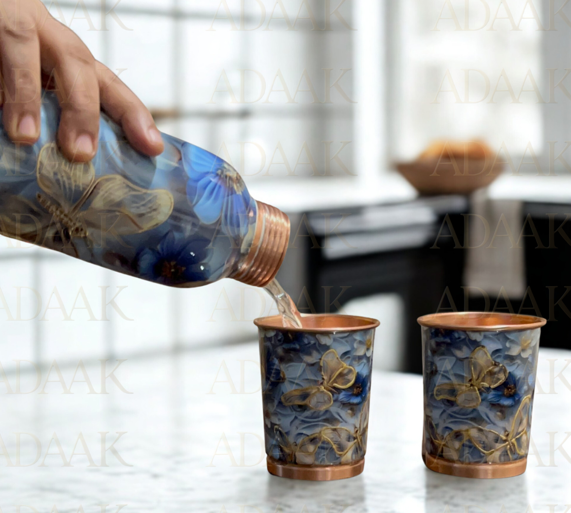 Copper cups with butterfly design being filled with a liquid.