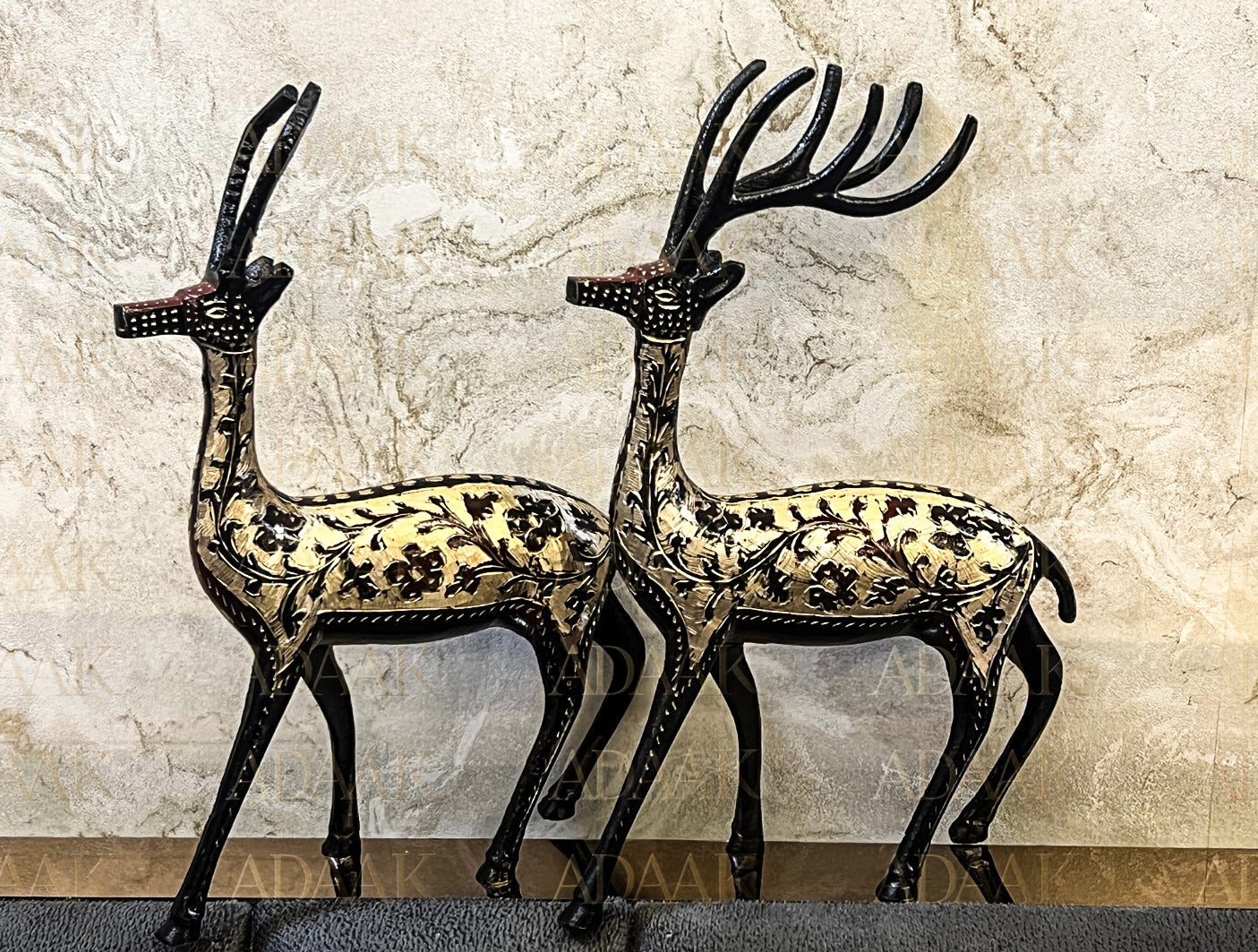 Decorative metal deer figures with intricate designs on a textured wall background