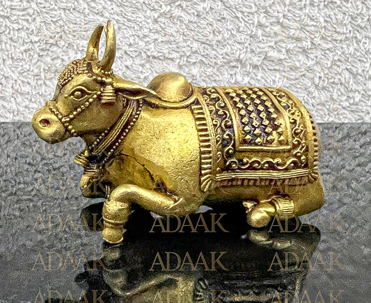 Decorative Brass Nandi on a reflective surface with 'ADAAK' branding.