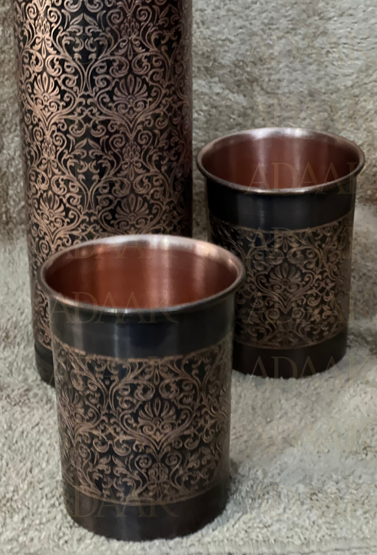 Set of two decorative copper cups with antique patterns on a textured surface