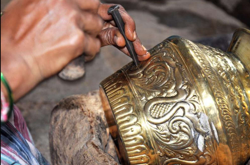 Artisan creating detailed engravings on a traditional brass vessel