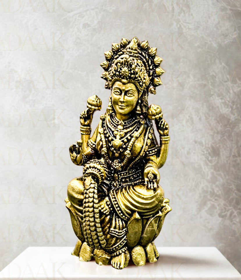 Brass statue of a deity on a white pedestal with a gray background
