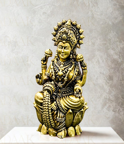 Brass statue of a deity on a white pedestal with a gray background